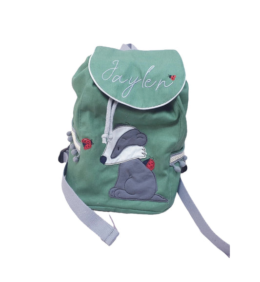 Kinder-Rucksack in Grün mit Dachs-Motiv, personalisiert mit Namen “Jaylen”, aus Baumwollcanvas, Magnetknopf, Seitentaschen, Maße 30 x 25 x 10 cm.